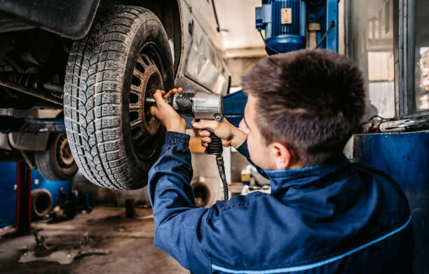 Auto mechanic changes a tire on car in a repair shop.